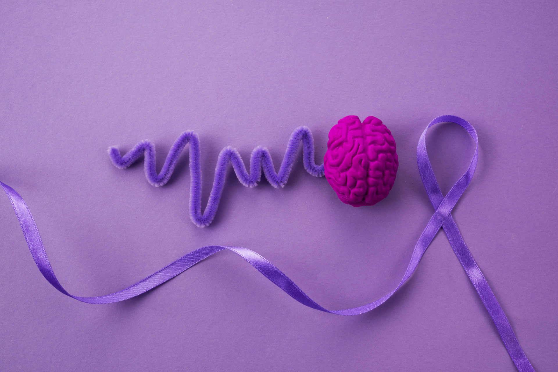 Epilepsy awareness ribbon beside a brain model with an EEG wave